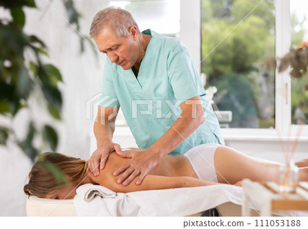 male masseur giving massage to female patient 111053188
