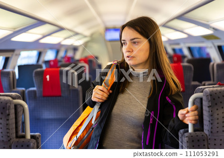 Woman standing between seats in train Woman standing between seats in train 111053291