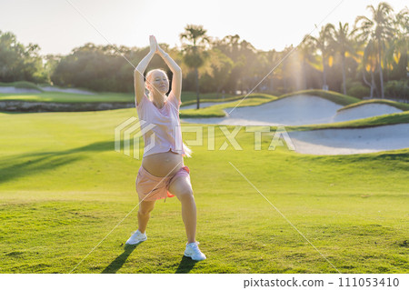 Energetic pregnant woman takes her workout outdoors, using an exercise mat for a refreshing and health-conscious outdoor exercise session 111053410