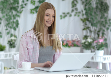 Portrait of young woman using laptop at home 111053512