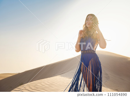 Woman in sands dunes of desert at sunset Woman in sands dunes of desert at sunset 111054890