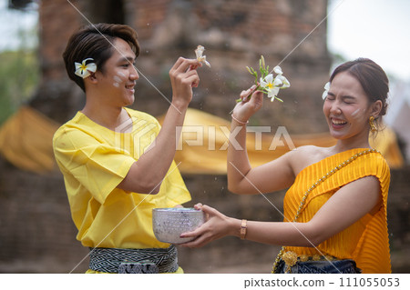 A beautiful Young Thai couple wearing Thai costumes playing in the water during Songkran in the temple 111055053