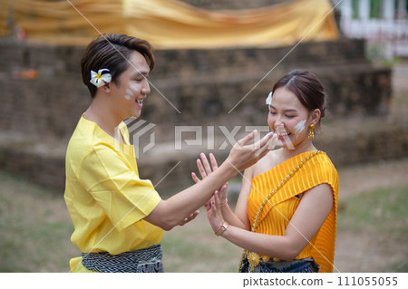 A beautiful Young Thai couple wearing Thai costumes playing in the water during Songkran in the temple A beautiful Young Thai couple wearing Thai costumes playing in the water during Songkran in the temple 111055055