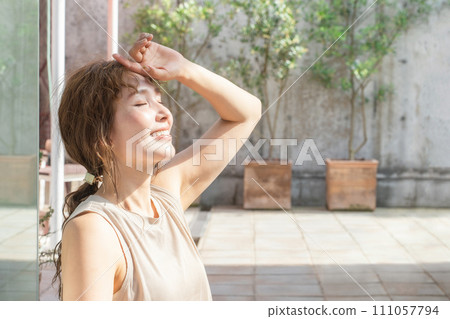 A woman sunbathing on the rooftop (sunshine, serotonin, sunscreen, ultraviolet rays, skin care) A woman sunbathing on the rooftop (sunshine, serotonin, sunscreen, ultraviolet rays, skin care) 111057794