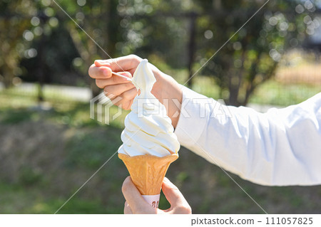 Scoop up the soft serve ice cream in your hand with a spoon 111057825