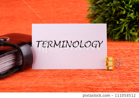 TERMINOLOGY text written on a white card near the business card holder in black on an orange background 111058512