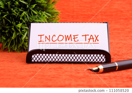 INCOME TAX text written on a white card on a stand on an orange background 111058520