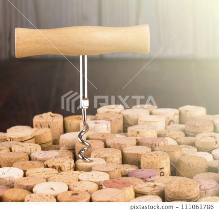 Corkscrew with a wooden handle against the background of wine bottle corks Corkscrew with a wooden handle against the background of wine bottle corks 111061786