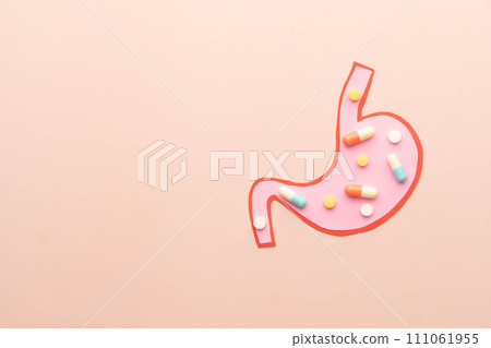 Stomach organ made from paper with medicine pills on beige color background. Creative ideas for probiotics, drug metabolism and gastrointestinal medication treatment concept. 111061955