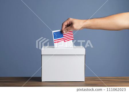 A hand inserts a ballot into a ballot box. 111062023