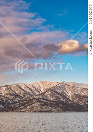 Snowy mountains and lake covered with clouds under the blue sky. 111062106