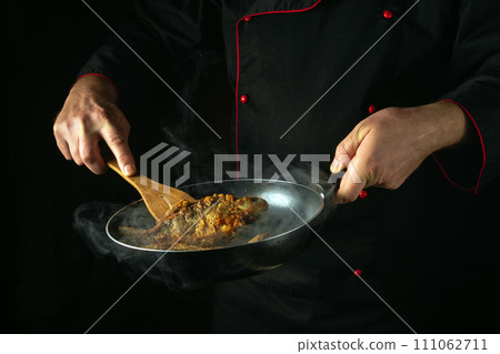 A chef prepares river fish in a restaurant kitchen. Fry the crucian carp in a frying pan. Idea for a delicious fish diet 111062711