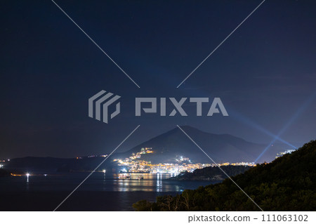 Lights of Budva riviera with rays in the dark sky 111063102