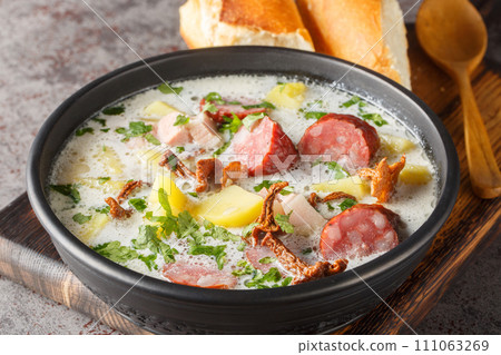 Zalewajka is a traditional rustic soup made of diced and boiled potatoes and overflowed with sour rye sourdough with sausage and dried mushrooms closeup on the plate. Horizontal Zalewajka is a traditional rustic soup made of diced and boiled potatoes and overflowed with sour rye sourdough with sausage and dried mushrooms closeup on the plate. Horizontal 111063269