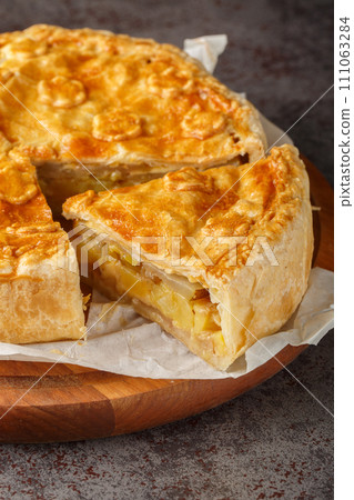 Walliser Cholera hearty pie with potatoes, apples and cheese closeup on the wooden board. Vertical Walliser Cholera hearty pie with potatoes, apples and cheese closeup on the wooden board. Vertical 111063284