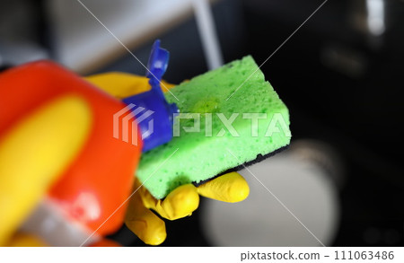 Gloved hands pour detergent for dishes on sponge 111063486