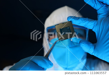 Man in uniform holds microprocessor with forceps 111063557