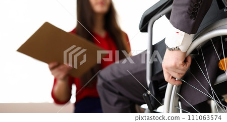 Man in suit on wheelchair communicates with woman 111063574