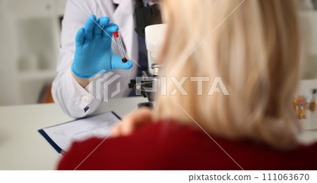 Doctor holds analyzed blood sample front patient Doctor holds analyzed blood sample front patient 111063670