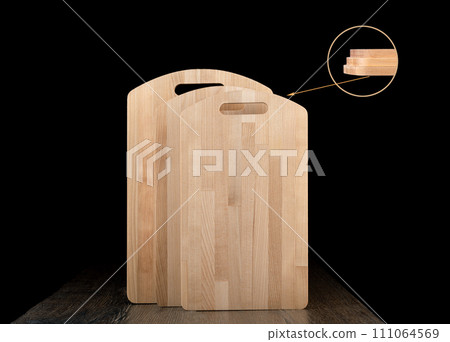Three new wooden cutting boards showing thickness on a dark background. Three new wooden cutting boards showing thickness on a dark background. 111064569