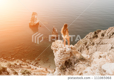 Woman travel sea. Happy tourist enjoy taking picture outdoors for memories. Woman traveler looks at the edge of the cliff on the sea bay of mountains, sharing travel adventure journey 111065068