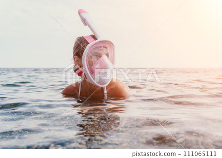 Young happy woman in white bikini and wearing pink mask gets ready for sea snorkeling. Positive smiling woman relaxing and enjoying water activities with family summer travel holidays vacation on sea. 111065111