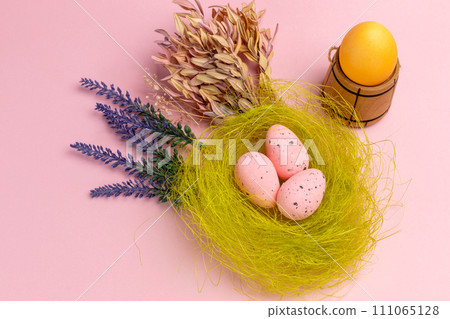 Nest with colored Easter eggs on the pink background. 111065128