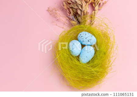 Nest with colored Easter eggs on the pink background. 111065131