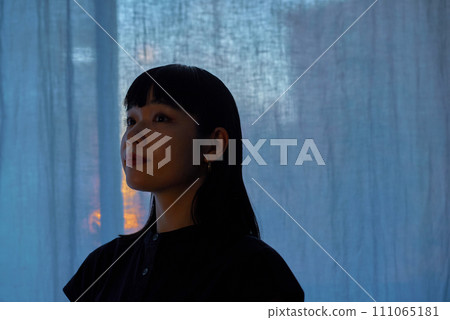 A young woman relaxing by the window at sunset A young woman relaxing by the window at sunset 111065181