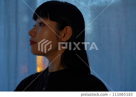 A young woman relaxing by the window at sunset A young woman relaxing by the window at sunset 111065183