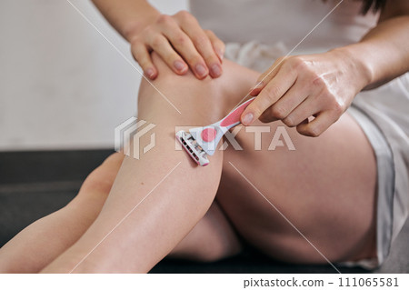 A woman in her 30s shaving her hair with a women's razor A woman in her 30s shaving her hair with a women's razor 111065581