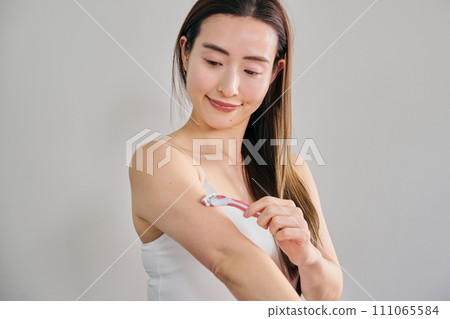 一名30多歲的女性用女士刮鬍刀剃掉手臂上的毛髮 111065584