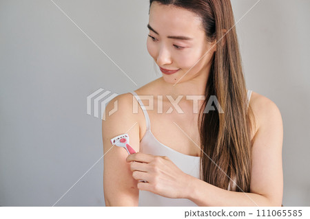 一名30多歲的女性用女士刮鬍刀剃掉手臂上的毛髮 一名30多歲的女性用女士刮鬍刀剃掉手臂上的毛髮 111065585