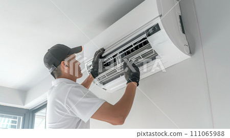 Man repairs an air conditioner indoors at home. Man repairs an air conditioner indoors at home. 111065988
