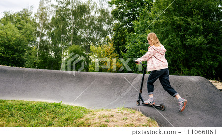 Preteen girl riding scooter on ramp in the park. Cute child with eco vehicle outdoors 111066061