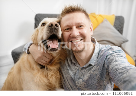 Portrait of Smiling man taking selfie with his cute golden retriever dog 111066091
