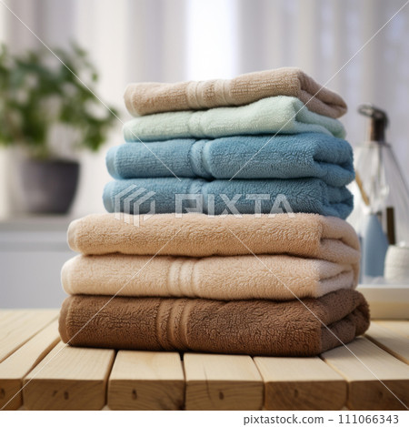 Stack of pastel colored folded towels on wooden table in bathroom. Stack of pastel colored folded towels on wooden table in bathroom. 111066343