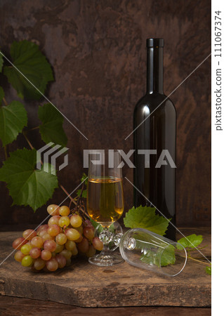 Still life with glass of white wine and grapes on vintage wooden background.. Still life with glass of white wine and grapes on vintage wooden background.. 111067374