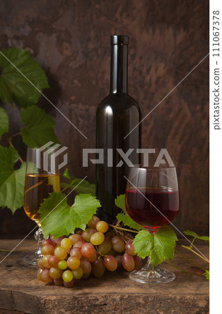 Still life with glasses of red and white wine and grapes on vintage wooden background.. Still life with glasses of red and white wine and grapes on vintage wooden background.. 111067378
