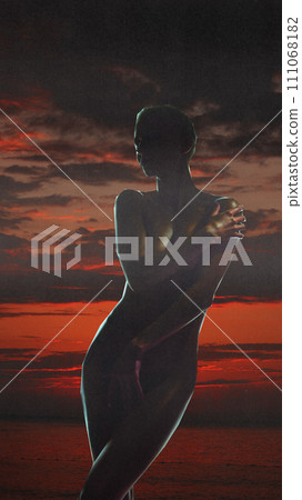 Passion, sensuality and inner power of woman. Silhouette of slim young woman over dark sunset sky. Conceptual creative design. Passion, sensuality and inner power of woman. Silhouette of slim young woman over dark sunset sky. Conceptual creative design. 111068182