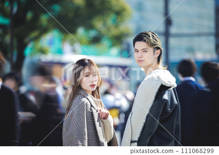 Portrait of a young man and woman standing on a street corner looking at the camera Portrait of a young man and woman standing on a street corner looking at the camera 111068299