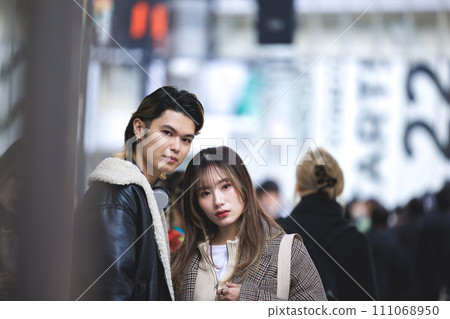 Portrait of a young man and woman standing on a street corner looking at the camera 111068950
