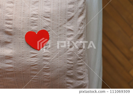 Valentine's Day, red card in shape of heart lies on pillow on bed in bedroom Valentine's Day, red card in shape of heart lies on pillow on bed in bedroom 111069309