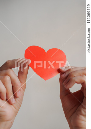 women's hands holding red heart shaped postcard, surprise gift for Valentine's day. women's hands holding red heart shaped postcard, surprise gift for Valentine's day. 111069329