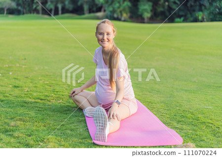 Energetic pregnant woman takes her workout outdoors, using an exercise mat for a refreshing and health-conscious outdoor exercise session 111070224