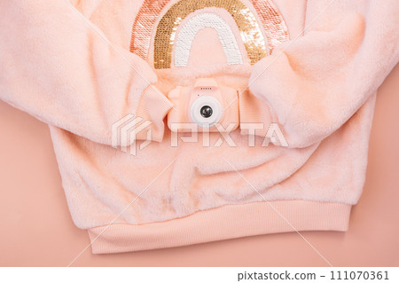 Children's pink jacket holding a digital camera on a pink background Children's pink jacket holding a digital camera on a pink background 111070361