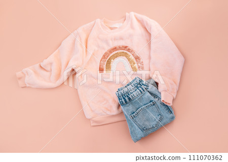 Children's pink sweater and blue jeans on a pink background Children's pink sweater and blue jeans on a pink background 111070362