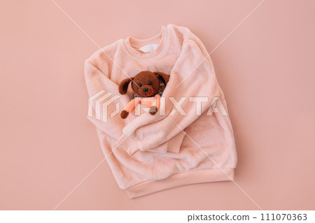 Soft pink jacket hugging a stuffed toy on a pink background Soft pink jacket hugging a stuffed toy on a pink background 111070363