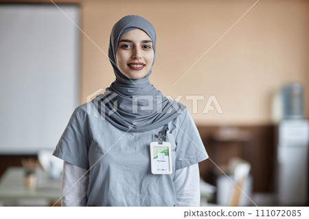 Portrait of happy Muslim woman doctor wearing gray hijab and scrubs looking at camera in medical center Portrait of happy Muslim woman doctor wearing gray hijab and scrubs looking at camera in medical center 111072085