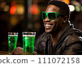 Cheerful Black man celebrating St. Patricks Day with a frothy green beer. Copy space 111072158